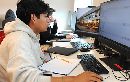 A student sitting and working on a computer in a classroom.